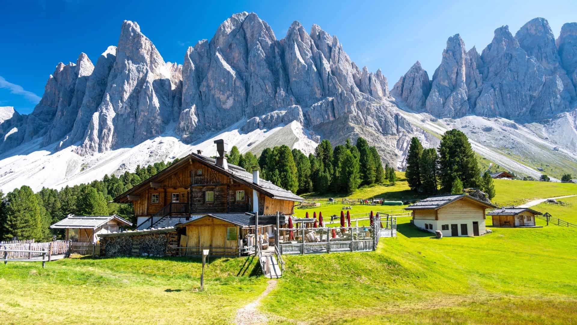 Eine Berghütte mit den Bergen des Val di Funes im Hintergrund
